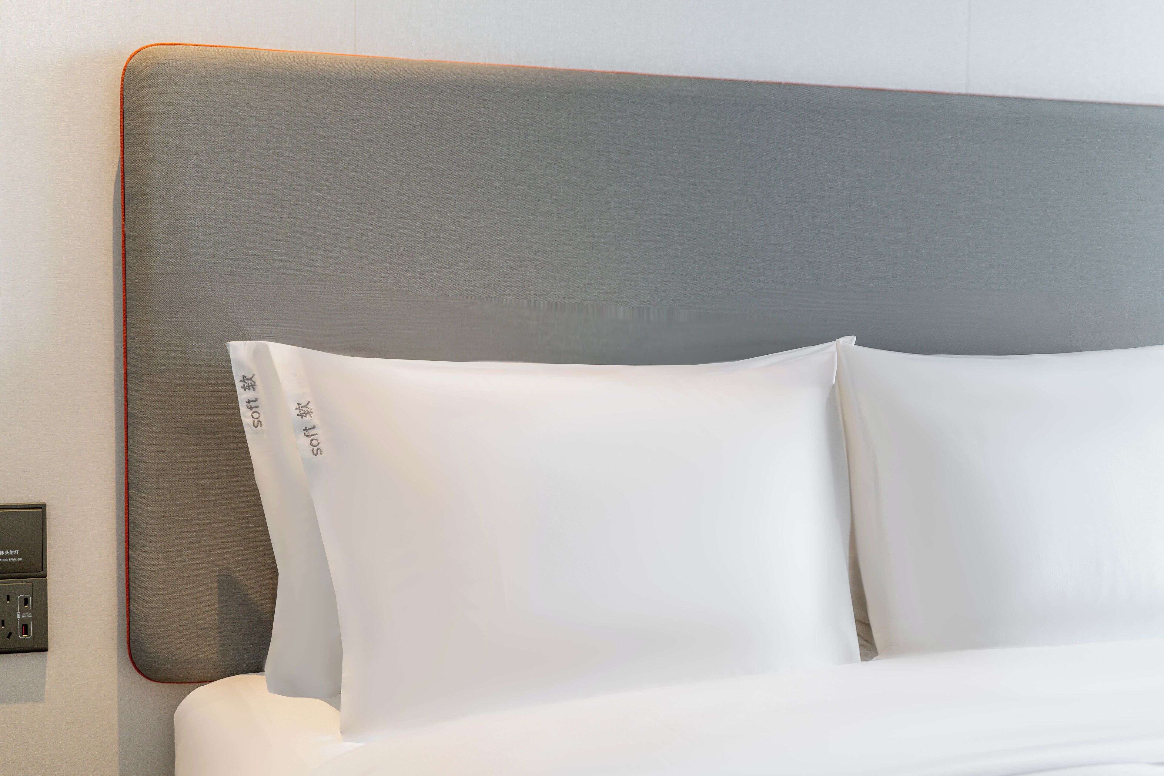Una cama con ropa de cama blanca y cabecera gris.
