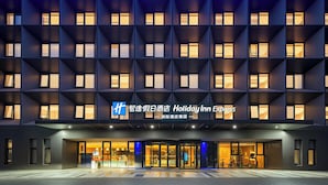 Ein Holiday Inn Express Hotel mit moderner Fassade, mehreren Balkonen und einem gut beleuchteten Eingang.