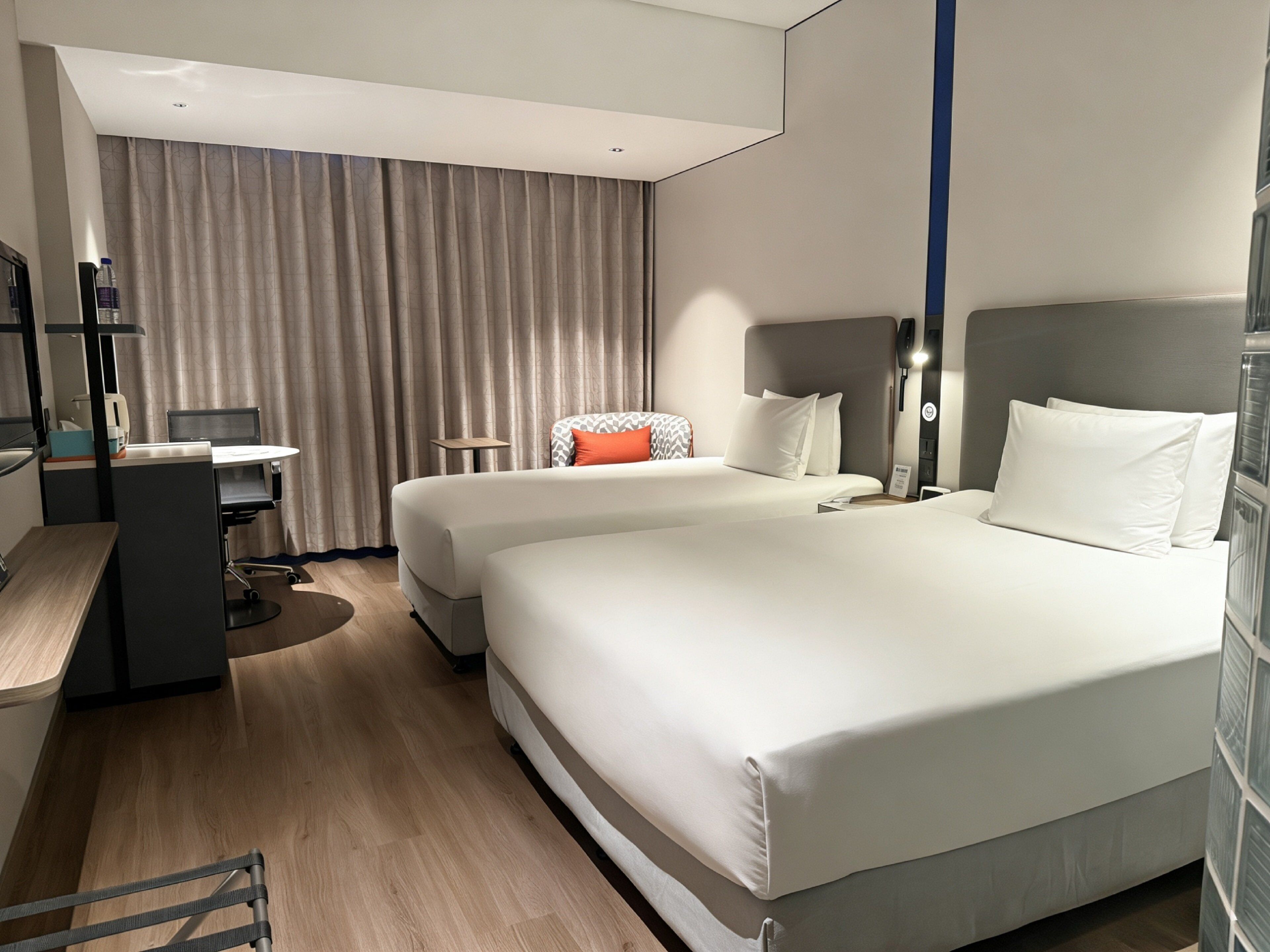 A hotel room with a large bed, a desk, a chair, and a small table.