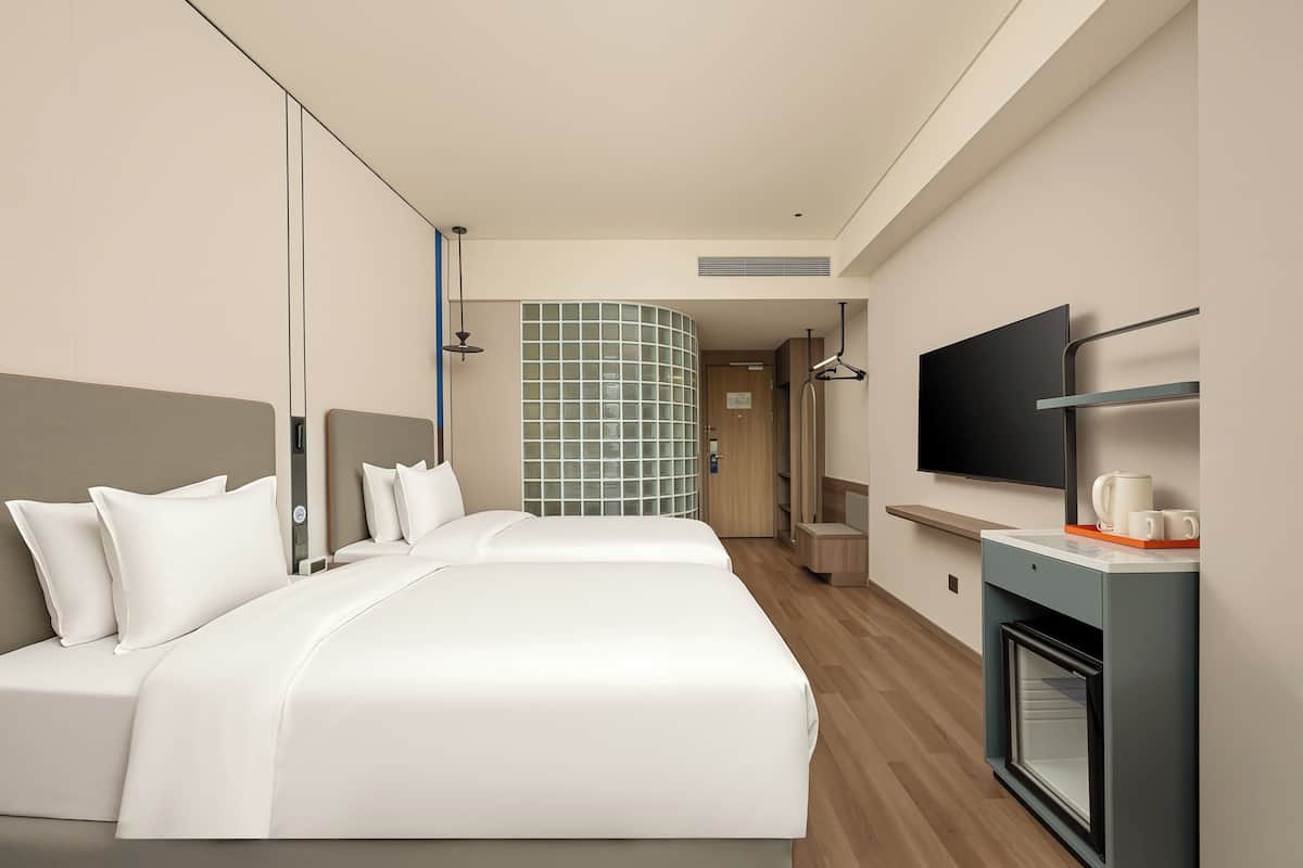 Ein Hotelzimmer mit einem großen Bett, einem Fernseher, einem Couchtisch und einer kleinen Küchenzeile.