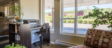 A reception area with a desk, chair, and a large window offering a view of the outdoors.