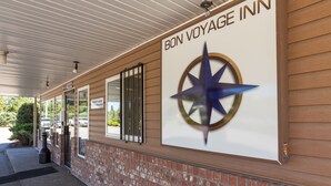 Exterior de un hotel con un letrero que dice "BON VOYAGE INN" y un logotipo de brújula.