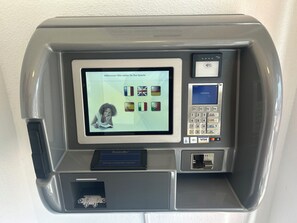 Una màquina de servei ràpid amb una pantalla que mostra opcions de llengua, un terminal de pagament amb Visa i un làpis per verificar la signatura.