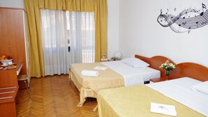 Habitación de hotel con dos camas, un escritorio de madera con frutero y una decoración musical en la pared.