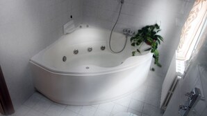 Un baño moderno con una bañera independiente, un cabezal de ducha y una planta en maceta.