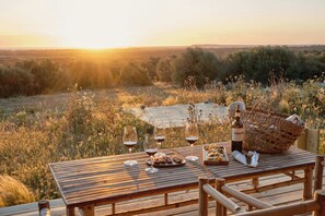 A wooden table set for a meal with wine glasses, a basket, and a bottle of wine. - Hotel Rural Morvedra Nou (Ciutadella de Menorca)