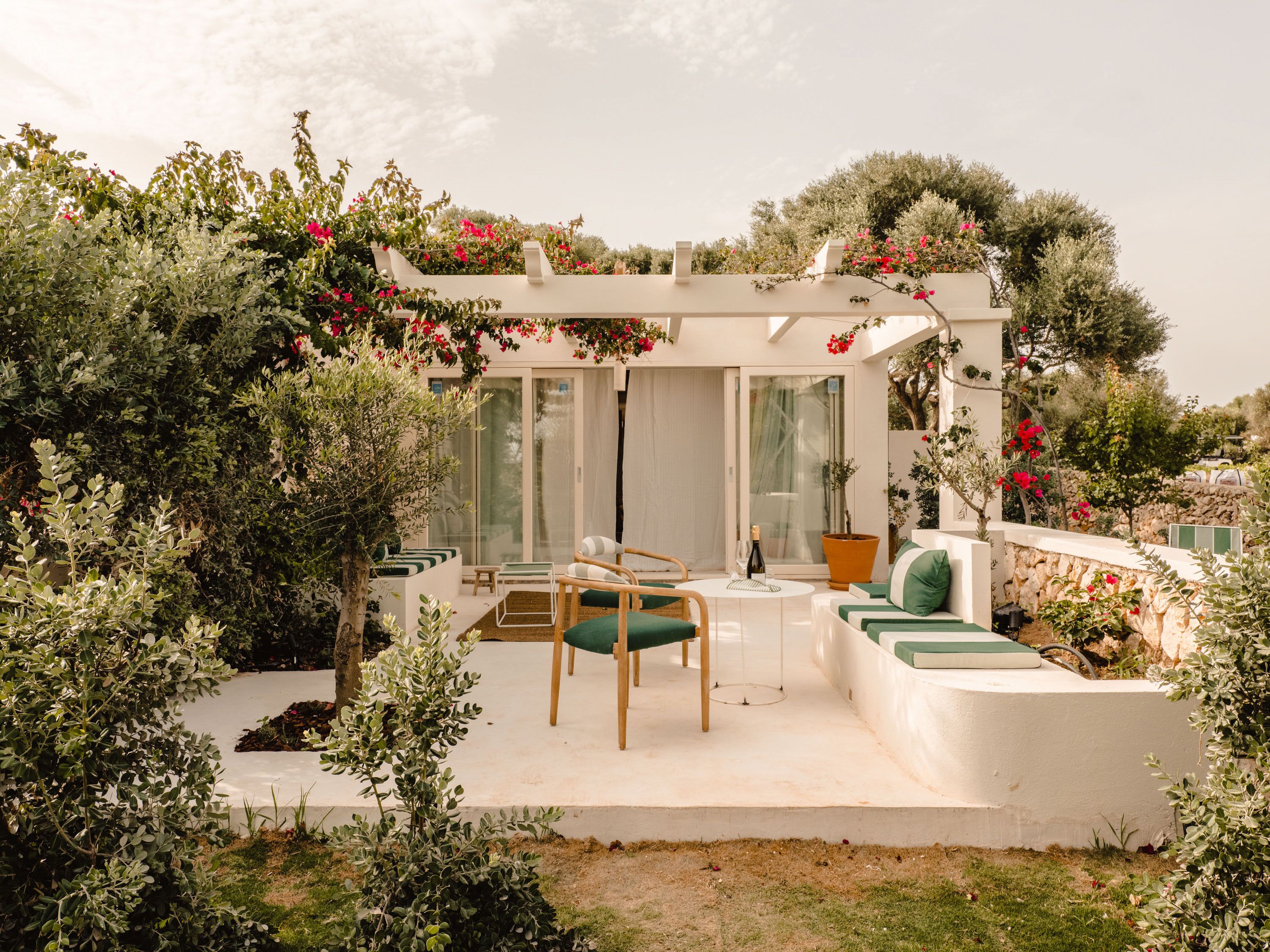 A patio with a seating area, a table, and a pergola with flowers.