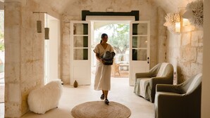 A room with a rustic, arched ceiling, a large white door leading outside, a round woven rug, and two upholstered chairs. - Hotel Rural Morvedra Nou (Ciutadella de Menorca)