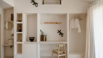 A minimalist room with a white desk, shelves, a chair, and a hanging light fixture.
