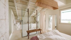 A bedroom with a bed, a bench, a large mirror, and a view of the outdoors. - Hotel Rural Morvedra Nou (Ciutadella de Menorca)