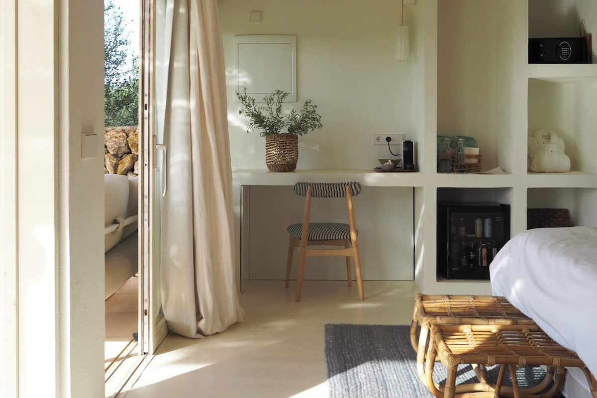 A bedroom with a bed, a desk, a chair, and a window with curtains.