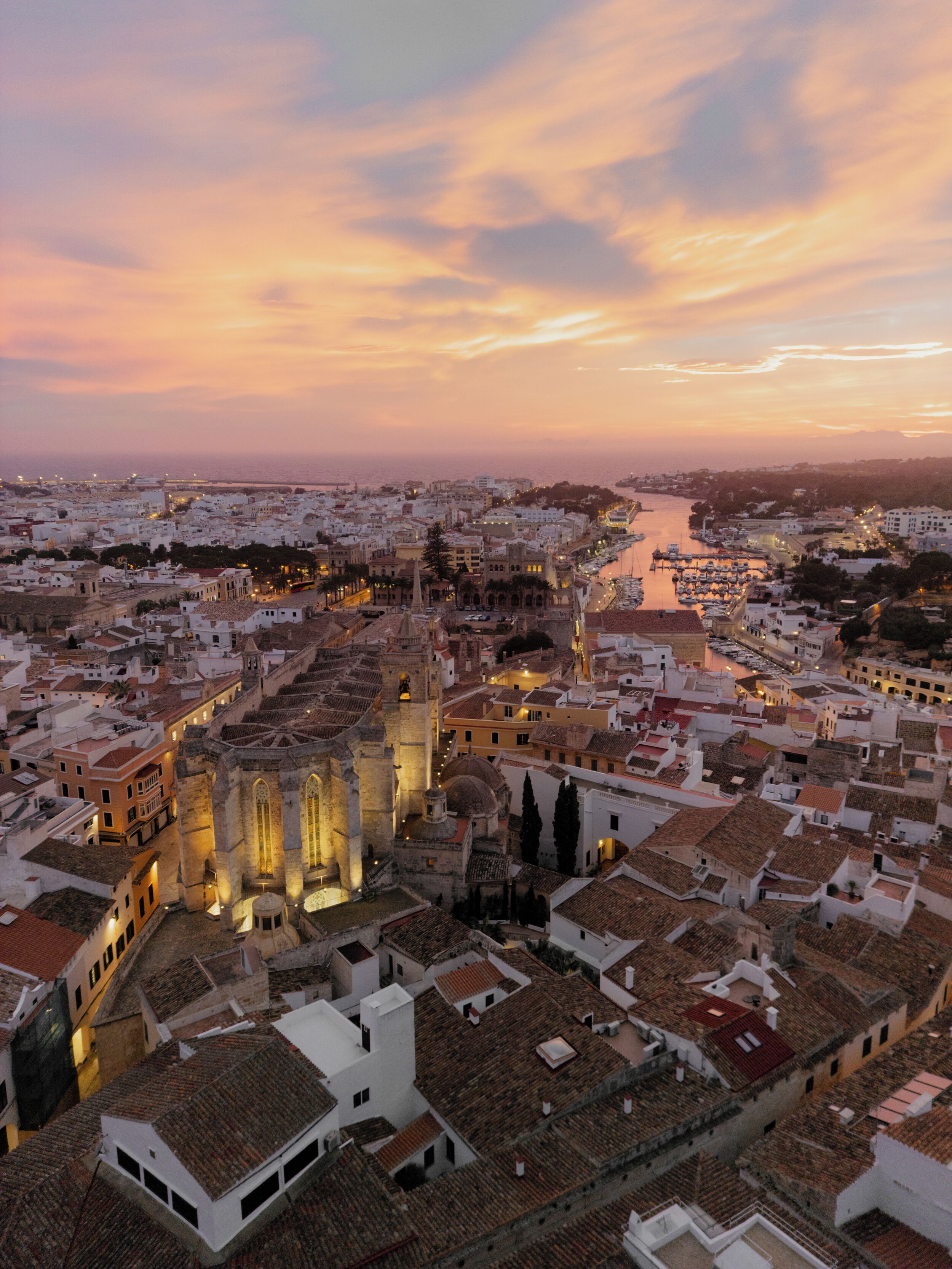 Un paisaje urbano histórico con una catedral destacada en el centro, rodeado de edificios tradicionales y un paseo marítimo.