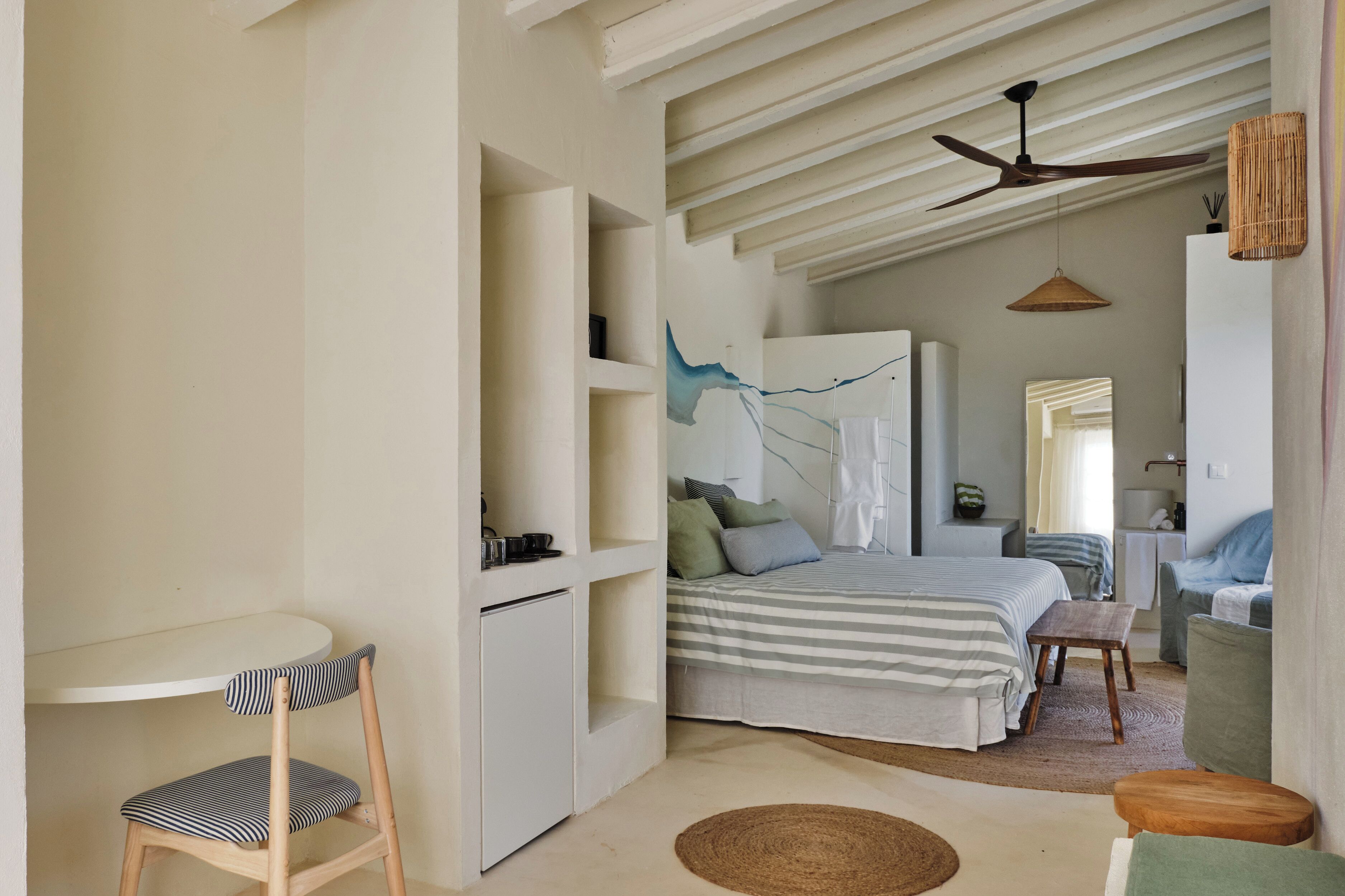 A bedroom with a bed, bedside table, chair, and a ceiling fan.