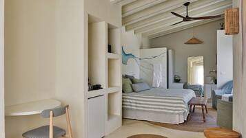 A bedroom with a bed, bedside table, chair, and a ceiling fan.