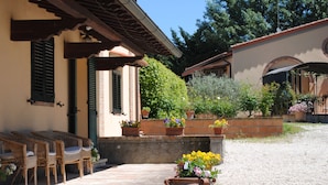 A courtyard with wicker furniture, potted plants, and a tiled floor. - Agriturismo Ai Prati (Perugia)