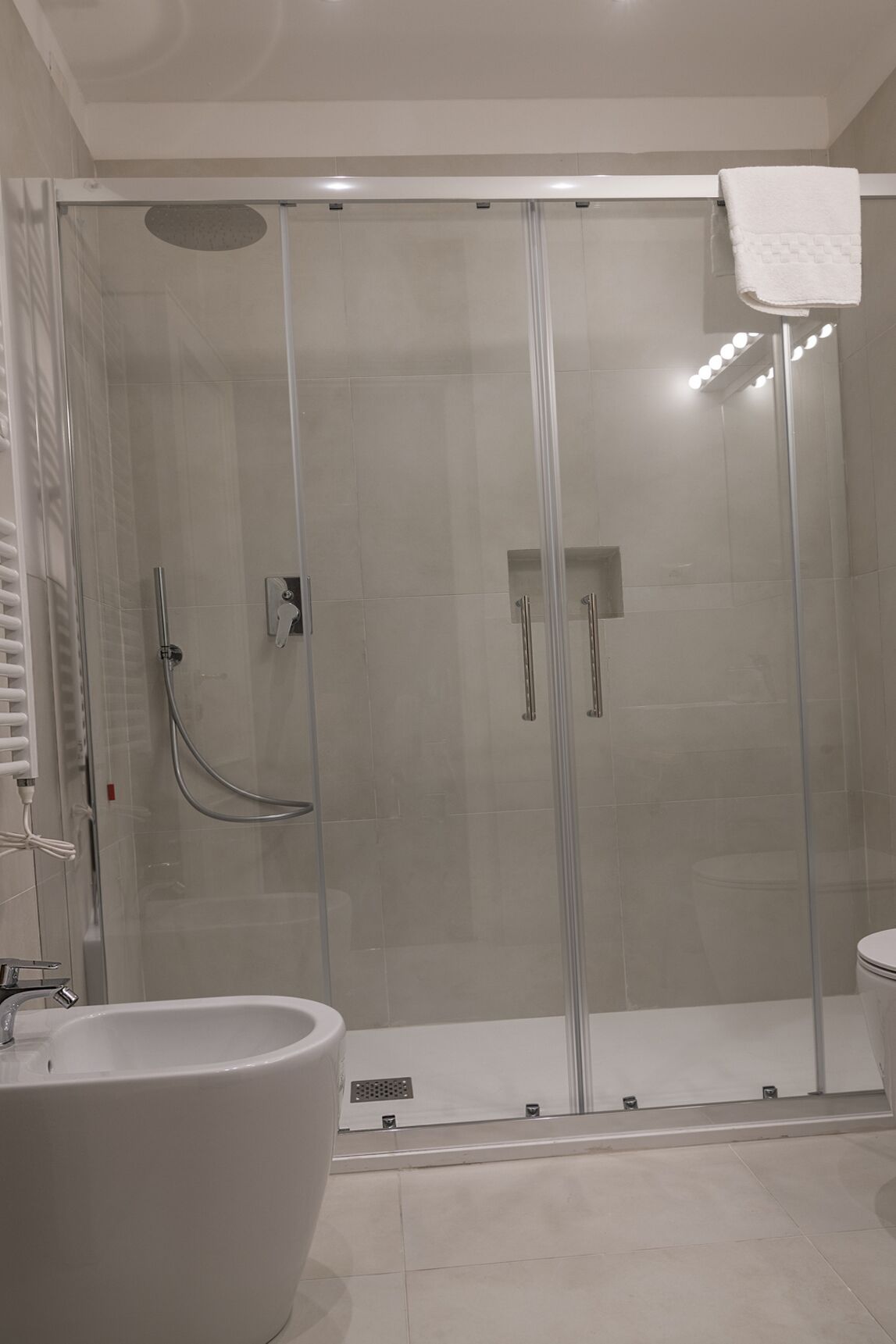 Un baño moderno con ducha envuelta en vidrio, una bañera independiente y un inodoro.