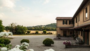 A building with a courtyard, gravel ground, and potted plants. - Agriturismo Ai Prati (Perugia)