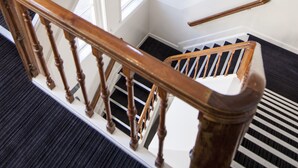 A staircase with wooden balusters and a handrail, leading to a landing with a window. - Hotel Iron Horse (Amsterdam)