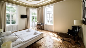 A hotel room with a large bed, a desk, a chair, a TV, and a lamp. - Home ApartHotel (Kraków)