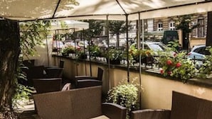 An outdoor seating area with wicker furniture and a table set with plates and cups. - Home ApartHotel (Kraków)