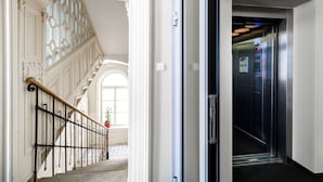 A modern elevator with a control panel and emergency stop button. - Home ApartHotel (Kraków)