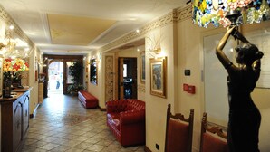 A hotel lobby with a red sofa, a chandelier, and a statue. - Alpina (Livigno)