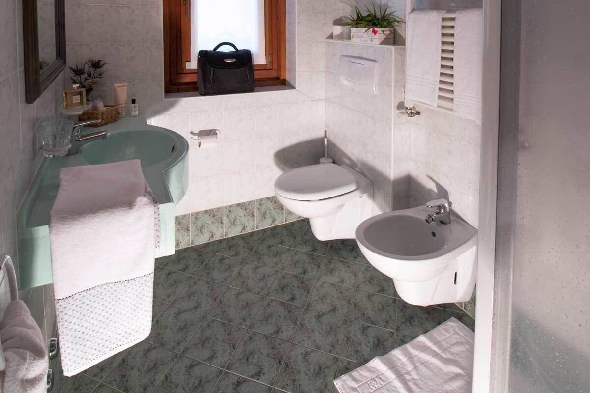 Un bagno con vasca, lavandino, WC e bidet. Una finestra offre vista all'esterno.