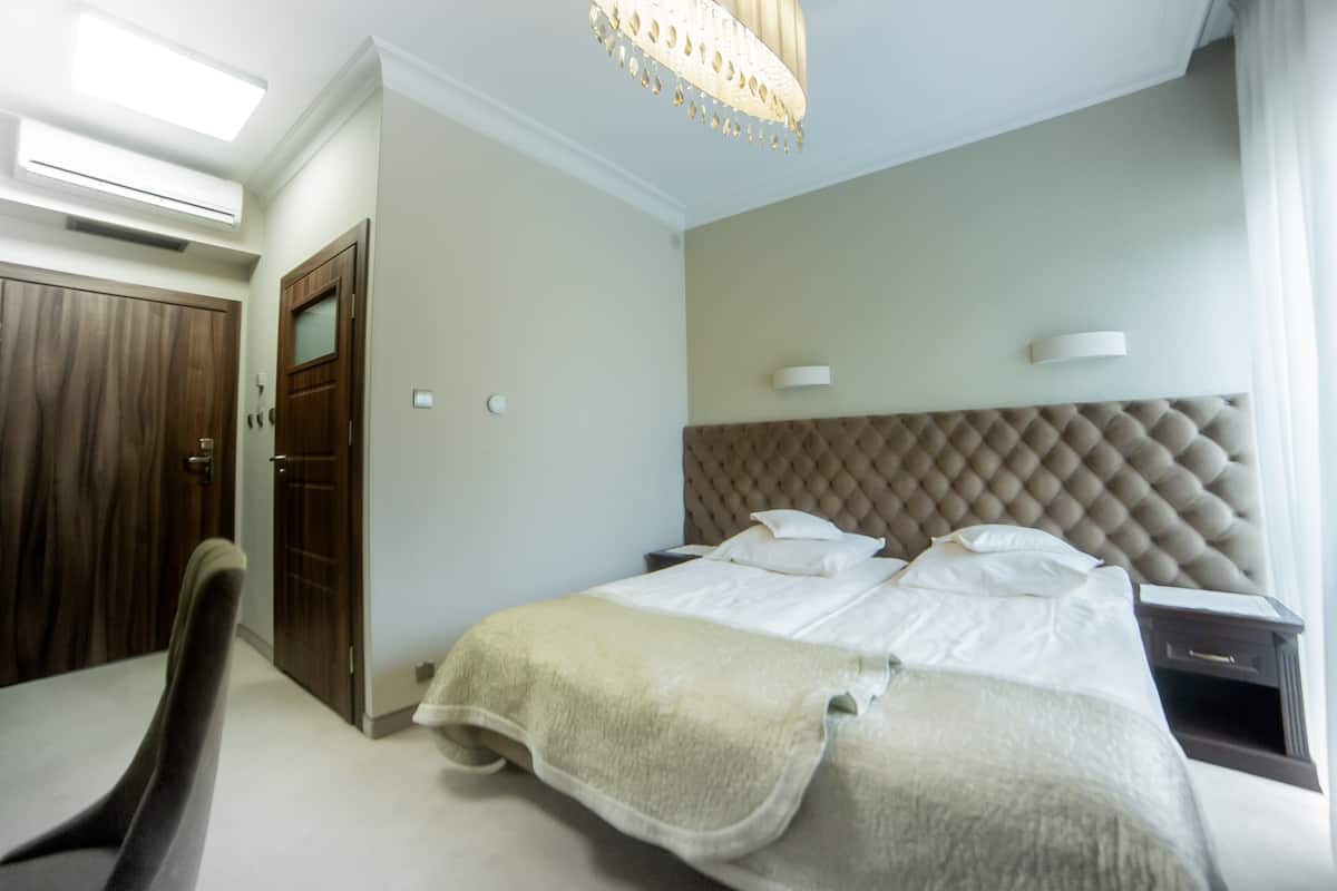 Ein ordentlich eingerichtetes Hotelzimmer mit einem großen Bett, einem Kleiderschrank und einem Schreibtisch mit Lampe.