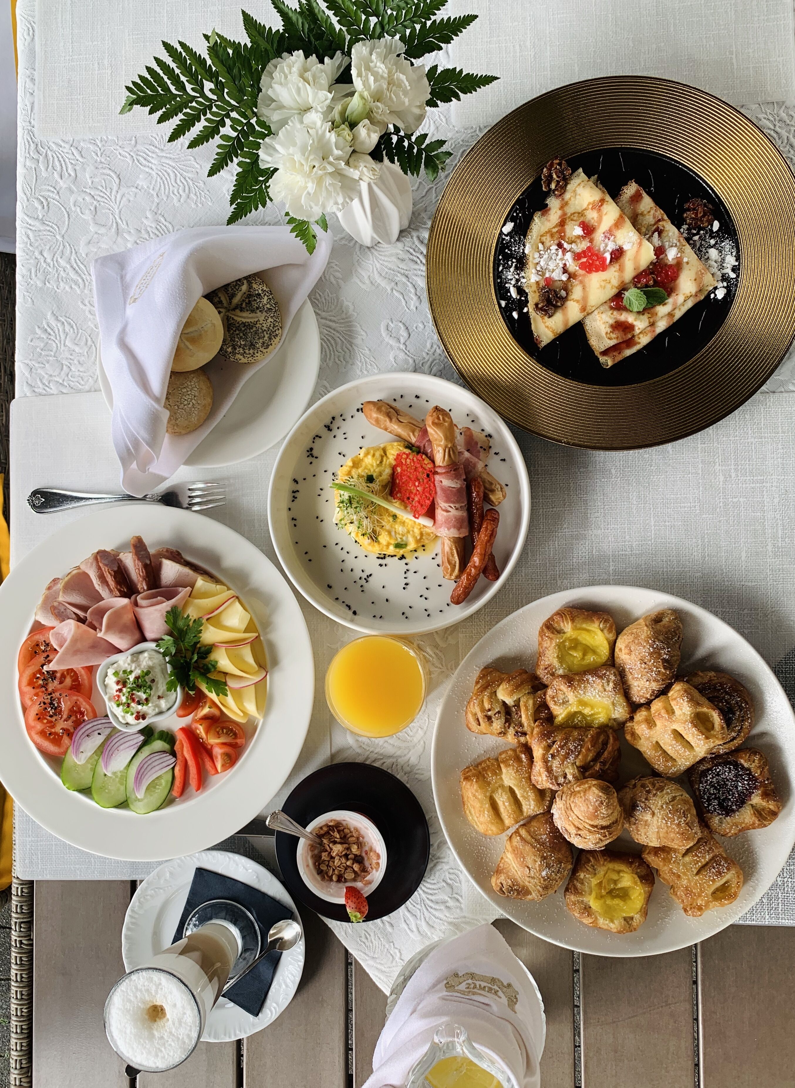 Un desayuno abundante con diversos platos, como pastelería, ensalada de frutas y una bandeja de carnes.