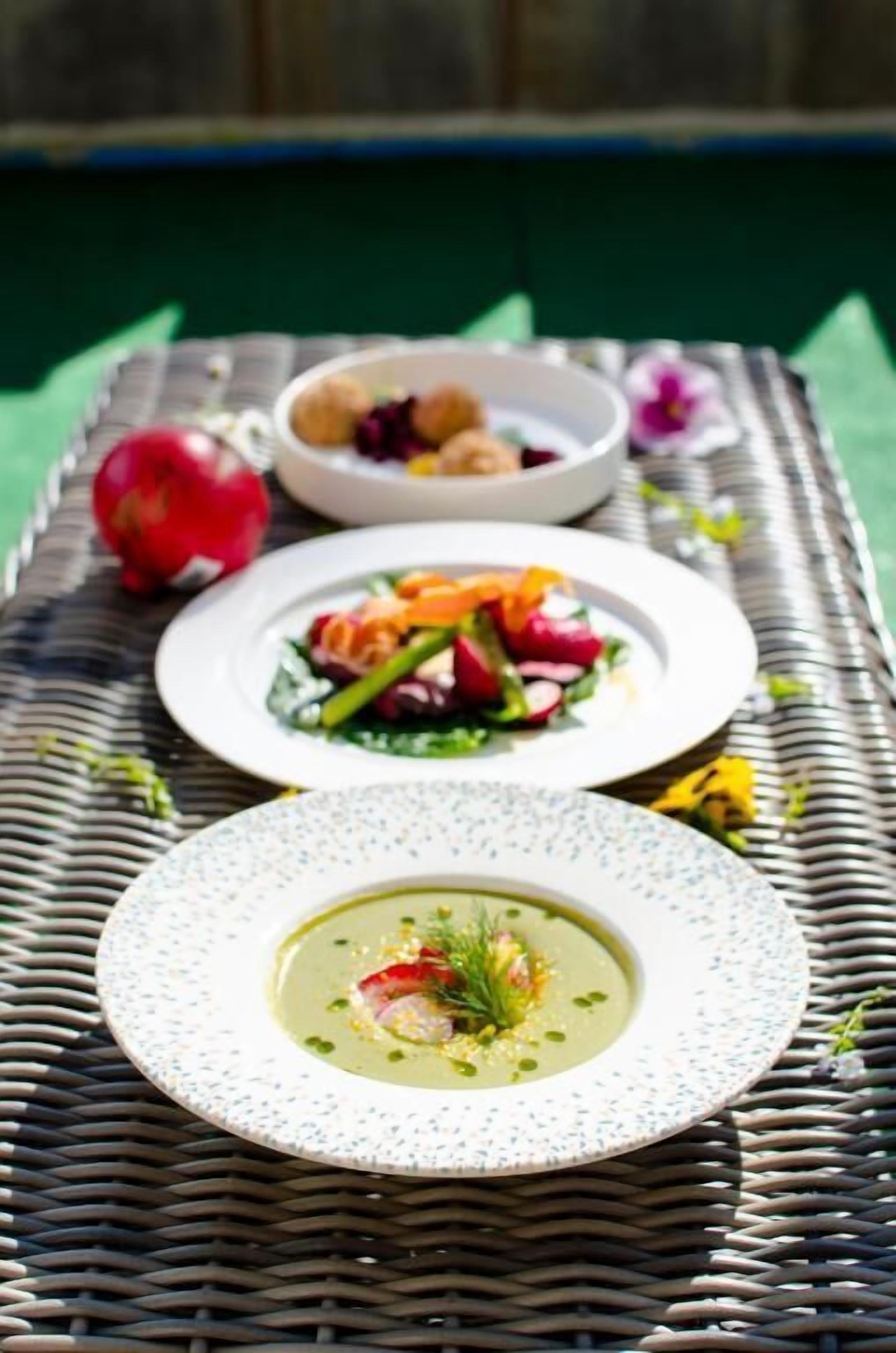 A dining table with plates of food, a bowl, and a decorative fruit.