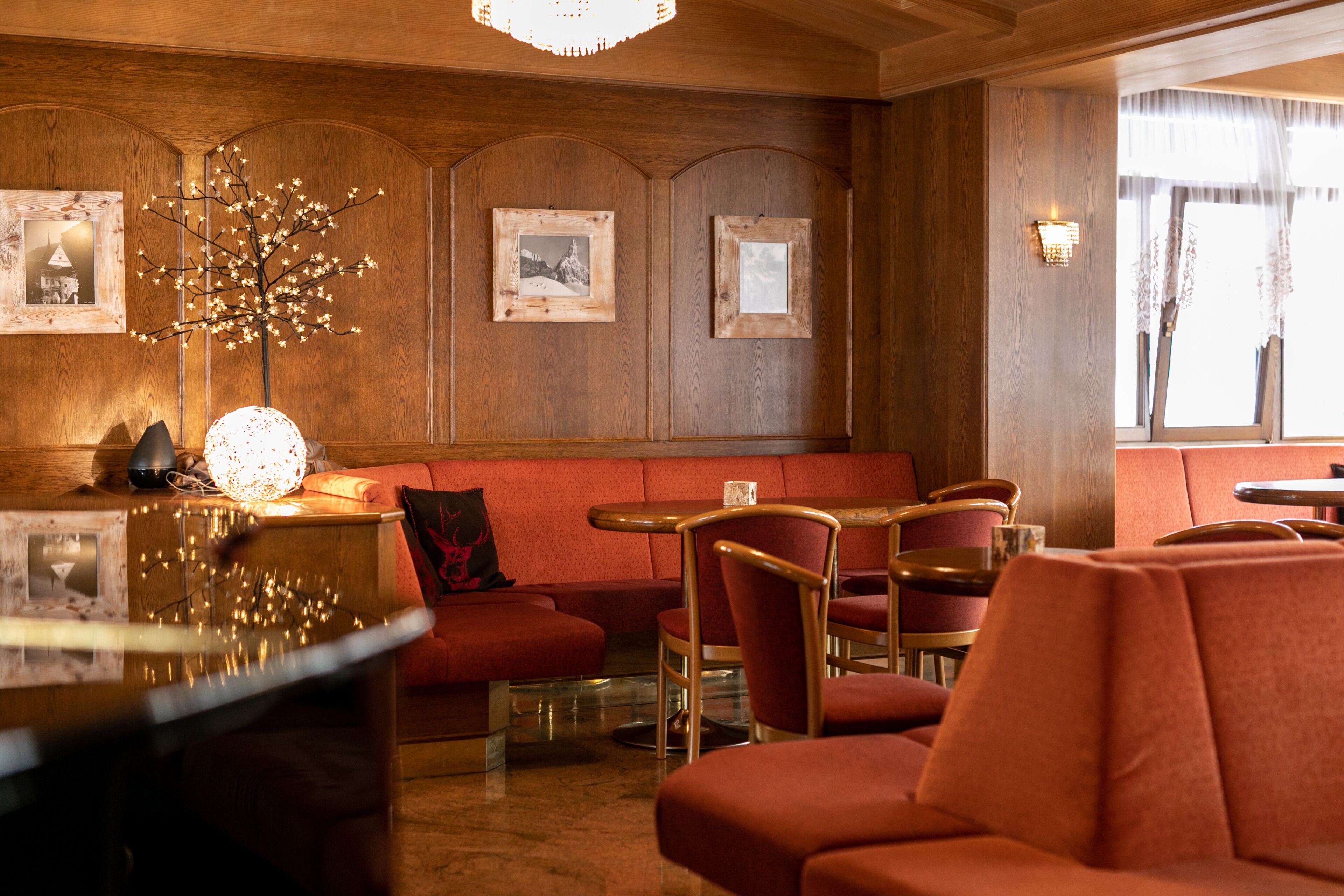 Ein gemütliches Restaurantambiente mit Holzwandverkleidung, rot gepolsterten Sitzmöbeln und gerahmten Bildern an den Wänden.