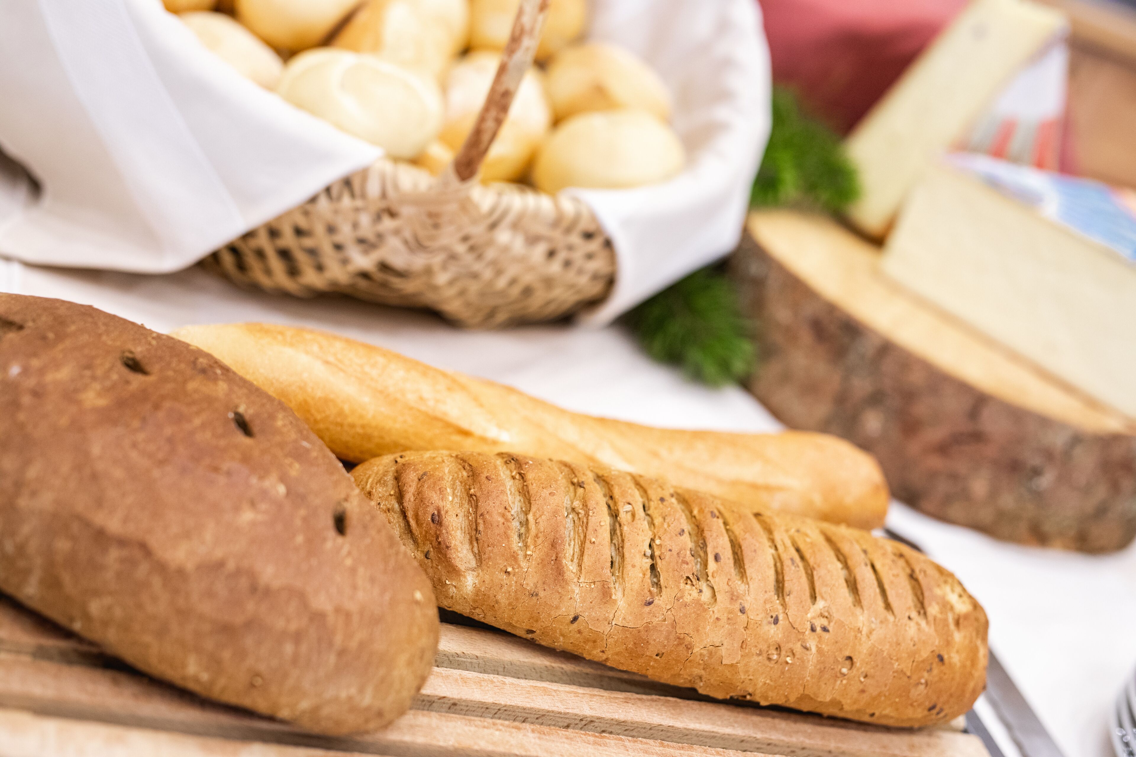 A variety of breads and cheeses on a wooden surface.