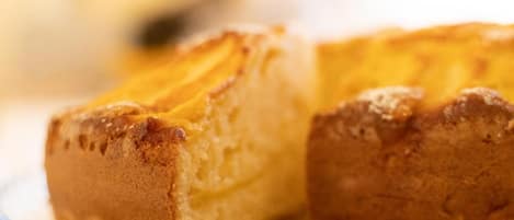 Primer plano de un producto horneado con corteza dorada, posiblemente un pastel o pan, sobre una superficie cubierta con un polvo blanco.