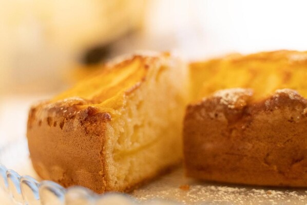 A close-up of a baked good with a golden-brown crust, possibly a pastry or bread, on a surface with a dusting of a white powdery substance.