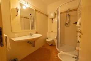 A bathroom with a sink, toilet, shower, and a mirror.