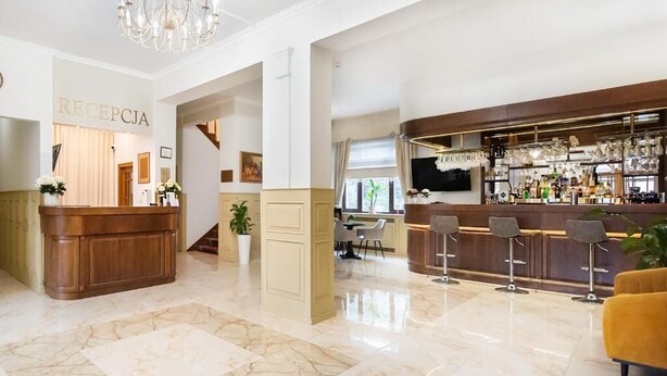 A hotel lobby with a reception desk, a bar area, and a staircase leading to another floor. - Arkadia (Warsaw)