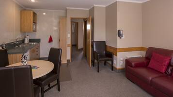 A compact living space with a kitchenette, a dining area, and a seating area with a red sofa.