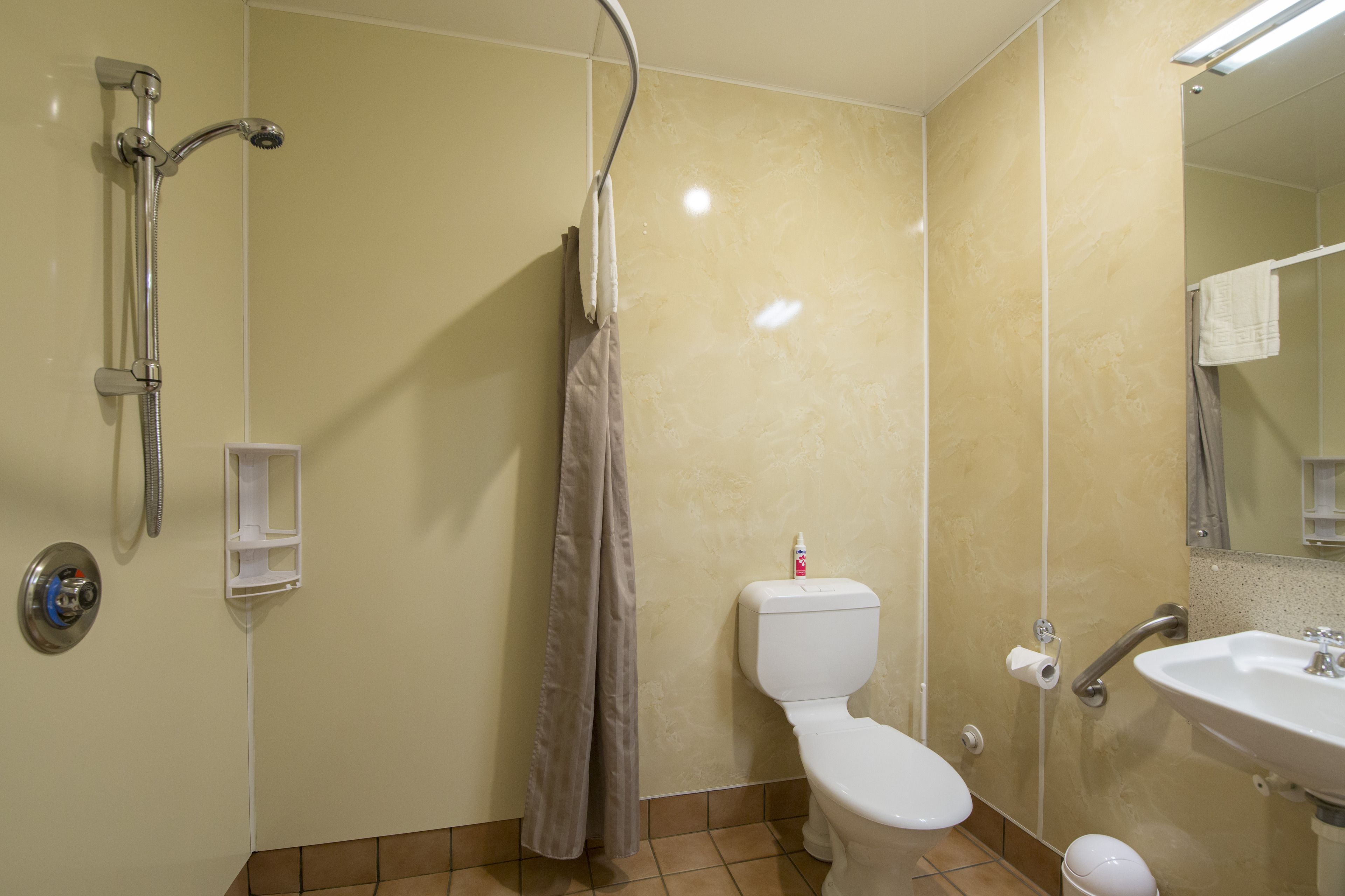 A bathroom with a shower, toilet, sink, and a mirror.