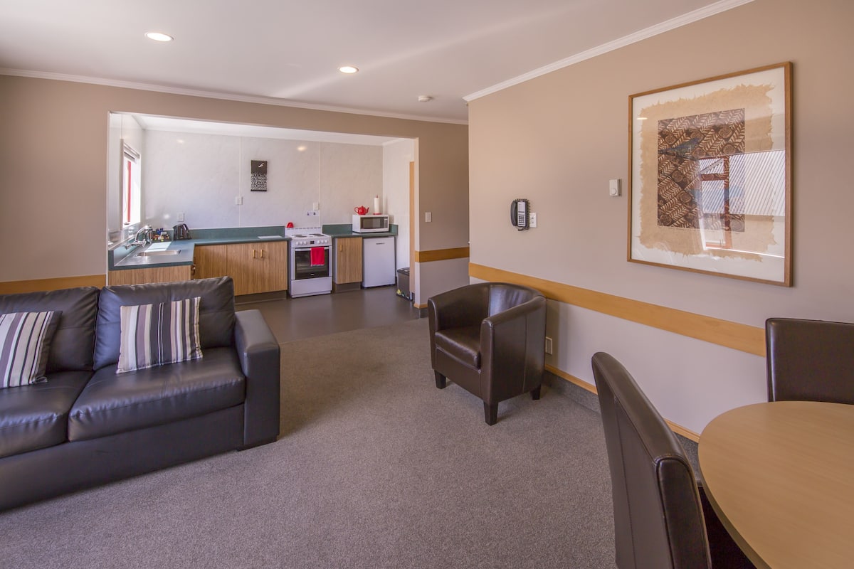 Un espacio habitable moderno con un sofá, una mesa de comedor y una cocina al fondo.
