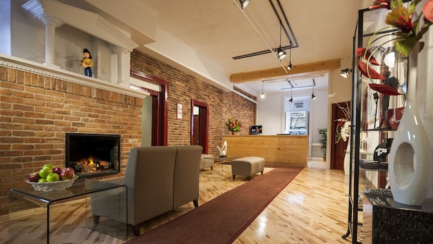 A modern living room with a brick fireplace, a sofa, a glass coffee table with apples, and a wooden reception desk.