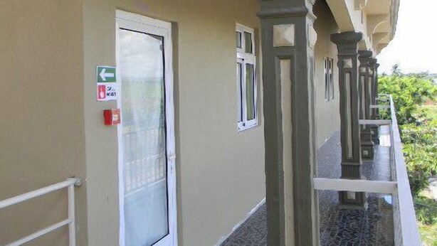 A corridor with a tiled floor, a door with a glass panel, and a balcony with a railing. - VillaOSoleil Apartments (Grand-Baie)