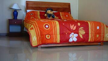Un letto con una coperta a fiori, un comodino con una lampada e un piccolo cassetto.