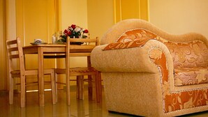 A cozy living room with a sofa, a dining table with chairs, and a vase of flowers. - VillaOSoleil Apartments (Grand-Baie)