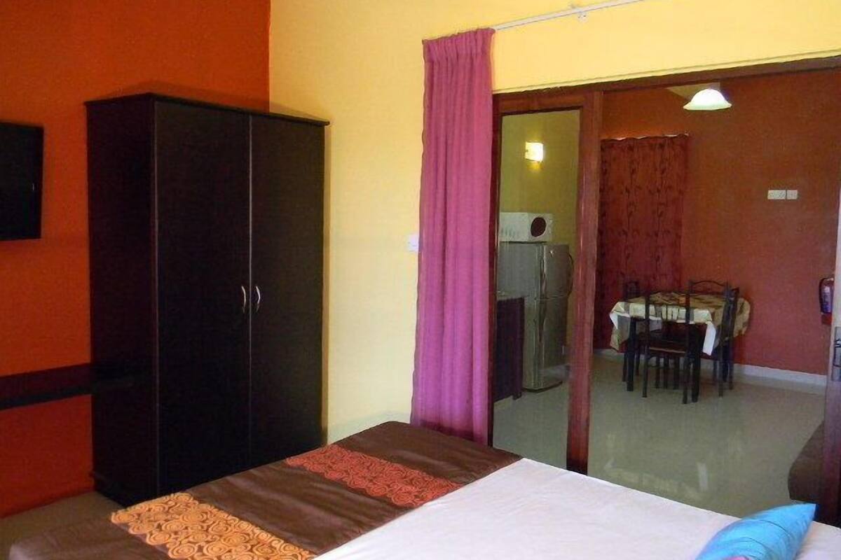 Ein Hotelzimmer mit Bett, einem Schrank, einer Essecke mit Tisch und Stühlen sowie einer Schiebetür zu einem weiteren Raum.