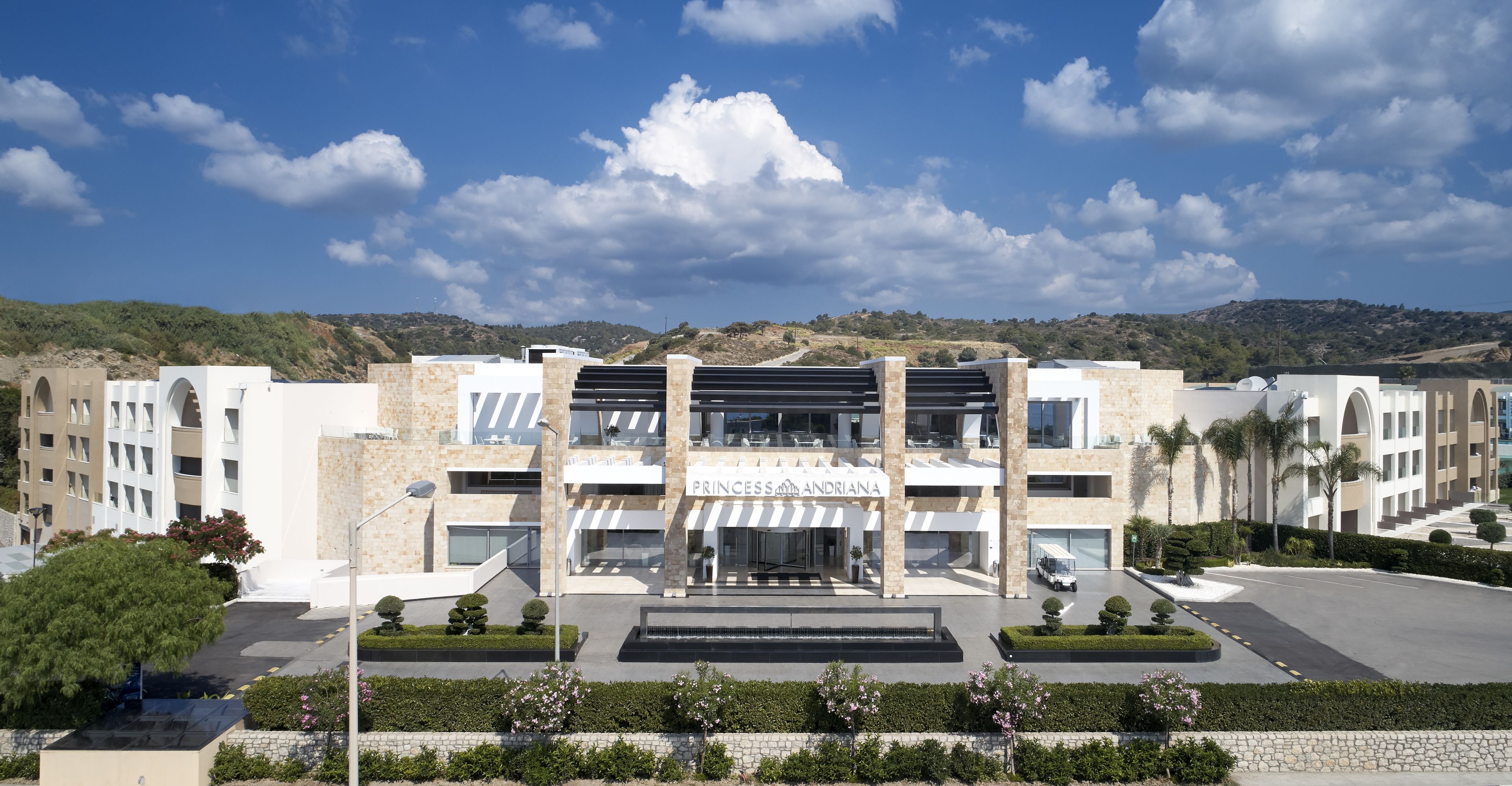 A modern hotel with a central entrance, multiple floors, and a landscaped courtyard.