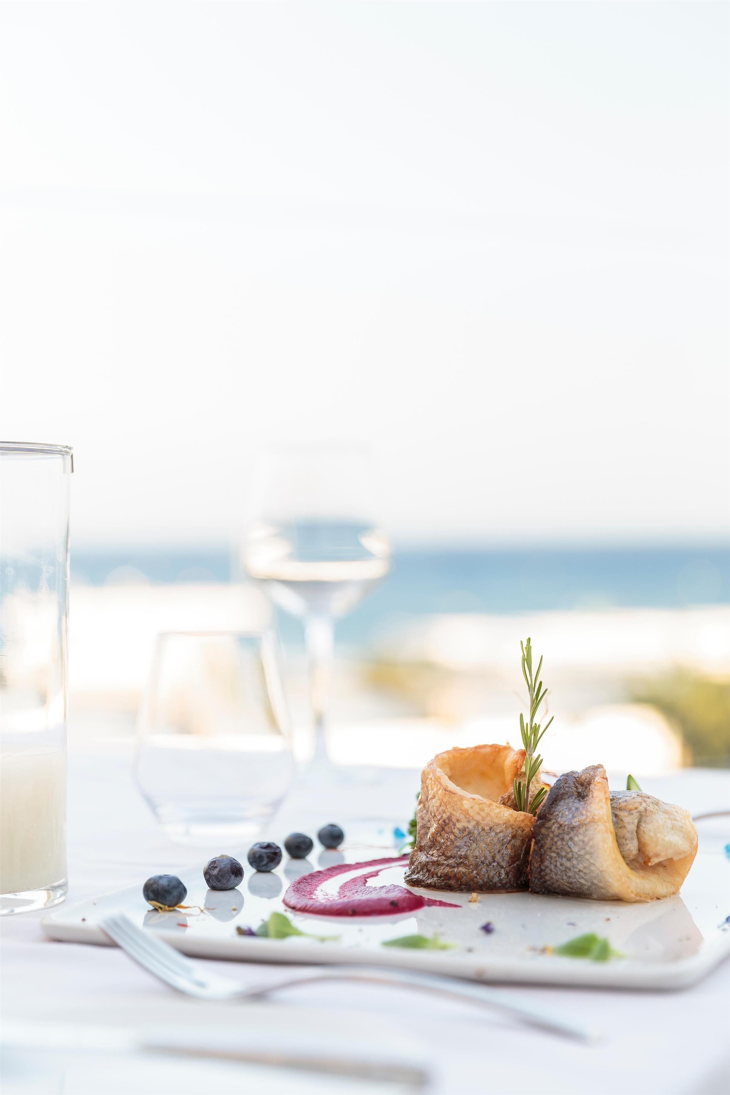A seafood dish on a white plate with a glass of milk and a glass of water on a table with a white tablecloth.