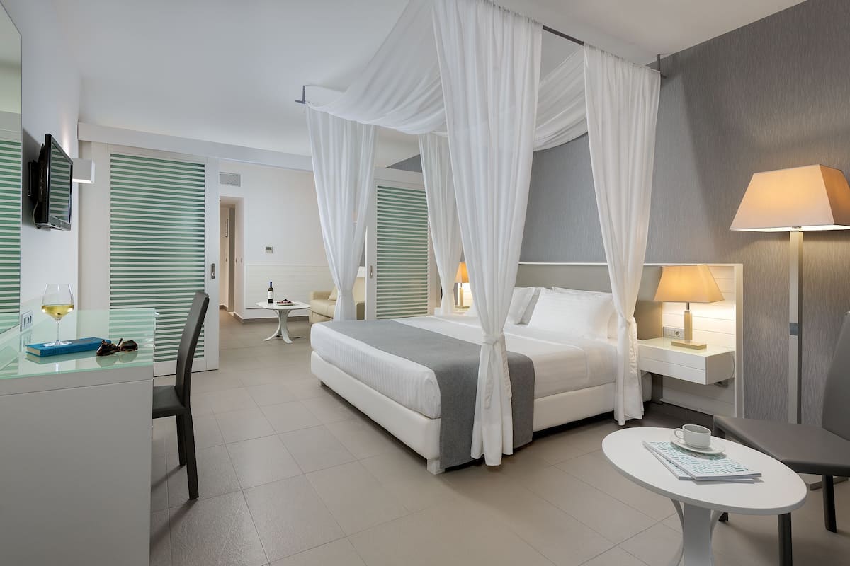 Quarto de hotel moderno com cama, escrivaninha, cadeira, mesa e televisão.