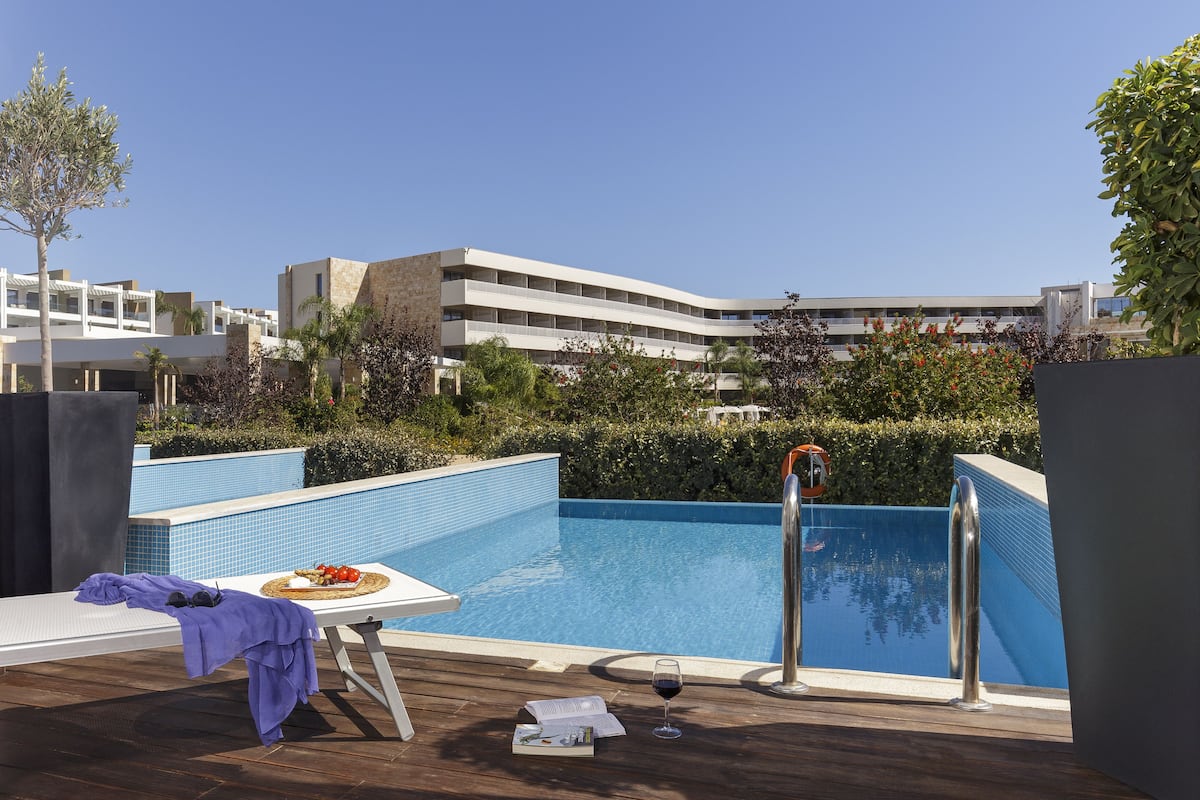 Uma área de piscina no terraço com uma espreguiçadeira, uma mesa com um livro e um copo de vinho, e uma vista desobstruída dos edifícios ao redor.
