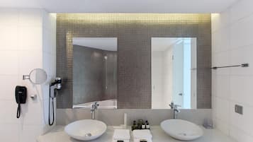 Un baño moderno con dos lavamanos, un espejo grande, un cabezal de ducha de mano y un teléfono.