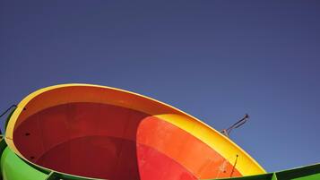 Una estructura grande, colorida y semicircular con fachada verde y interior amarillo y rojo, probablemente parte de un paseo de atracciones.
